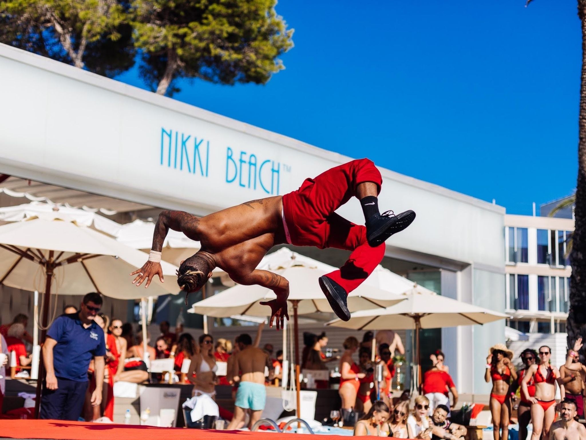 Víctor Óscar Juaranz realiza una acrobacia aérea sobre una tarima roja durante un espectáculo en Nikki Beach Ibiza, como parte de una animación organizada por su empresa OjoArtísticoEvents.