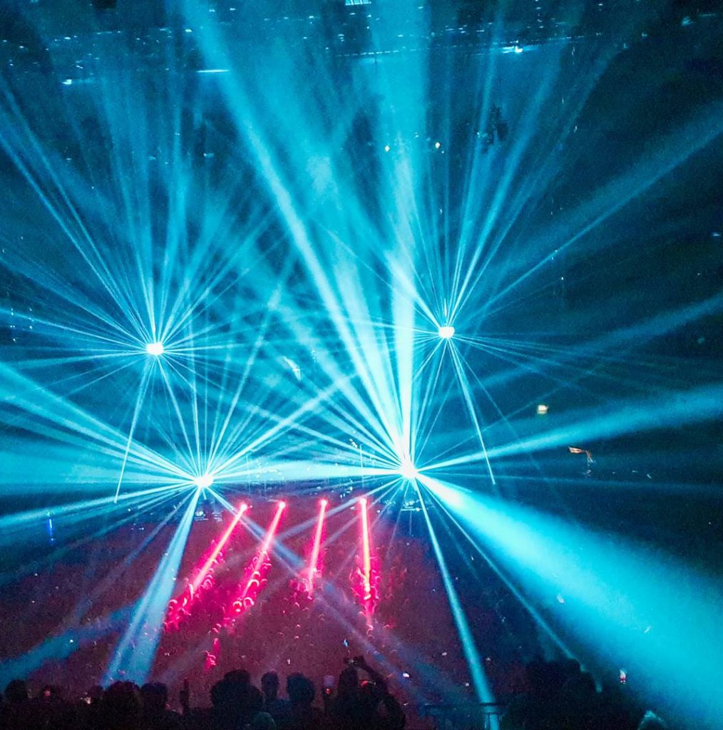 Montaje escénico con luces rojas y focos blancos en un evento visual.