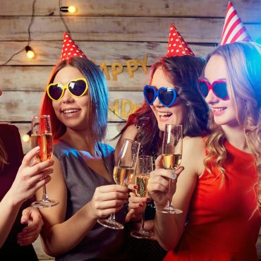 Grupo de mujeres jóvenes brindando con copas en una fiesta de cumpleaños.