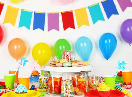 Mesa decorada con dulces, globos y colores vivos en una fiesta infantil.