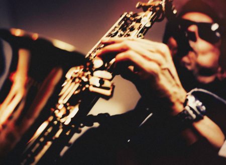Músico con gafas de sol tocando el saxofón en primer plano.