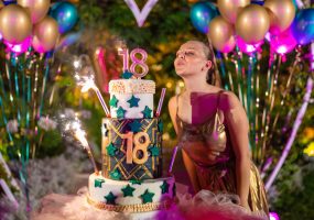 Joven festejando sus 18 años frente a una tarta decorada en una fiesta.