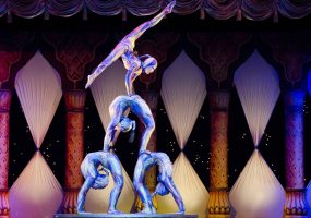 Cuatro acróbatas en equilibrio grupal, formando una figura escénica compleja.