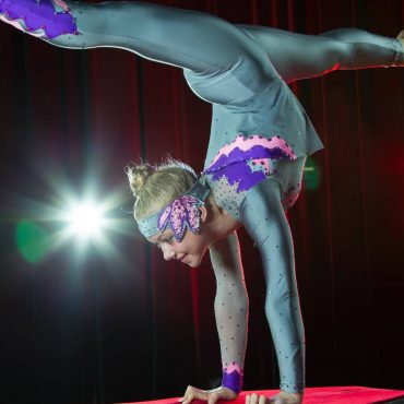 Acróbata en equilibrio sobre las manos, vestida con traje brillante.