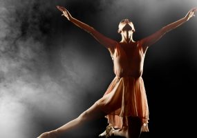 Bailarina contemporánea en pose expresiva, iluminada entre humo escénico.