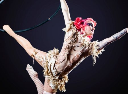 Acróbata aérea con vestuario teatral suspendida en un aro durante un espectáculo.