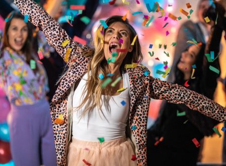 Mujer celebrando con confeti y expresión de alegría en una fiesta.
