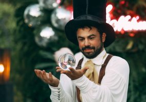 Artista con sombrero de copa manipula una esfera de cristal.