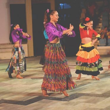 Grupo de bailarinas con faldas coloridas ejecutando danza folklórica.