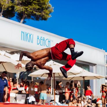 Víctor Óscar Juaranz realiza una acrobacia aérea sobre una tarima roja durante un espectáculo en Nikki Beach Ibiza, como parte de una animación organizada por su empresa OjoArtísticoEvents.